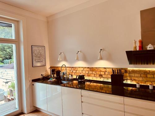 a kitchen with white cabinets and a brick wall at Villa am Strand in Eckernförde