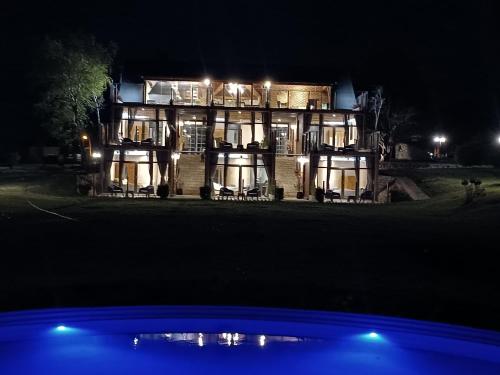 una casa grande por la noche con una piscina frente a ella en ROCCHETTA HOTEL BOUTIQUE en Sierra de los Padres