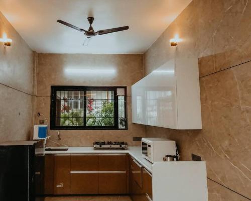 a kitchen with a ceiling fan and a microwave at Breeze The Hills By Stayvilla in Trimbak