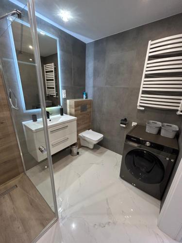 a bathroom with a sink and a washing machine at Apartament Jodłowa in Kołobrzeg