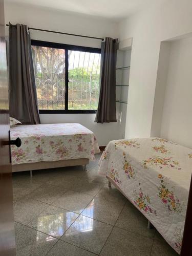 a bedroom with two beds and a window at APARTAMENTO SOL E MAR VITÓRIA in Vitória