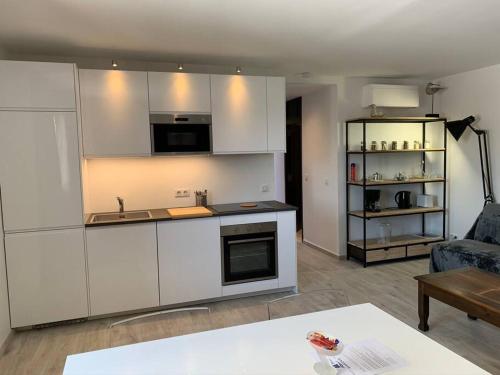 uma cozinha com armários brancos e uma sala de estar em Appartement neuf 4km Saint-Tropez em Saint-Tropez
