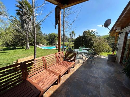 two wooden benches sitting on a patio with a pool at Casa Foresta - BBQ Cocina Piscina Mascota Wifi in Melipilla
