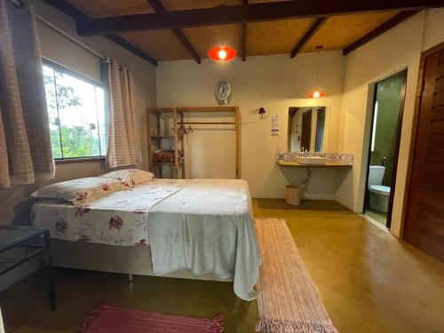 a bedroom with a bed and a sink in it at Vila Amor - Charmosa e Central in Alto Paraíso de Goiás