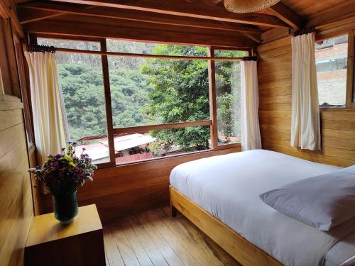 a bedroom with a bed and a large window at Tree House Lodge in Machu Picchu