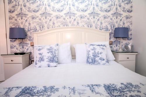 a bedroom with a white bed with blue floral wallpaper at The Cock and Bull in Balmedie