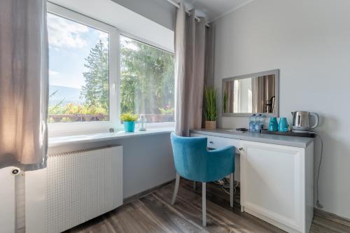 a kitchen with a blue chair and a window at Willa Sonata - w otoczeniu natury z widokiem na góry in Szklarska Poręba