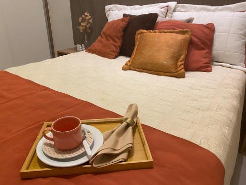 a tray with a cup of coffee on a bed at House Park completo em Blumenau-SC in Blumenau