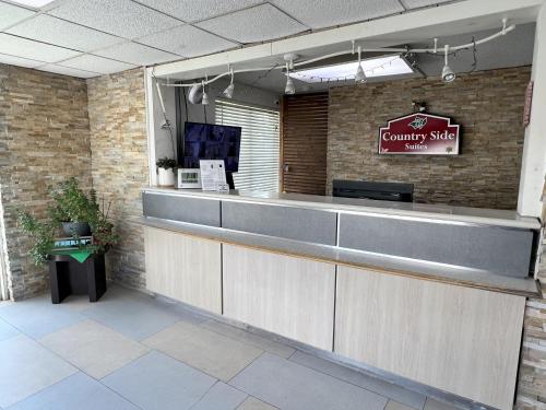 a restaurant counter with a sign on a brick wall at Countryside Suites Kansas City Independence I-70 East Sports Complex Hotel in Independence