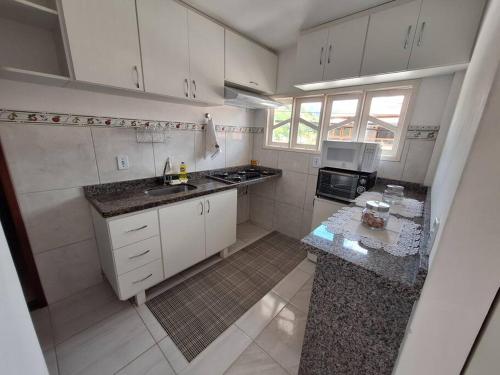 Elle comprend une petite cuisine avec des placards blancs et un évier. dans l'établissement Apartamento Venda Nova do Imigrante, à Venda Nova do Imigrante