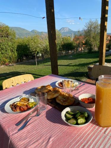 stół z talerzami jedzenia i szklanką soku pomarańczowego w obiekcie Country House Mitrovic w mieście Babušnica