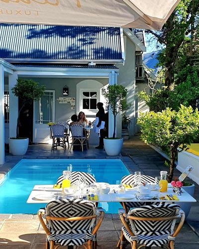 a patio with a table and chairs next to a pool at Fleur du Soleil Luxury Guesthouse in Franschhoek