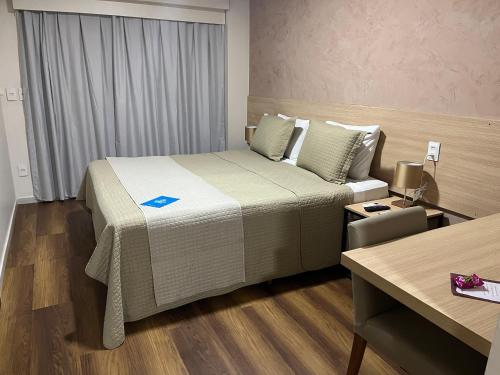 a hotel room with a large bed and a desk at Arrey Gran Hotel in Teresina