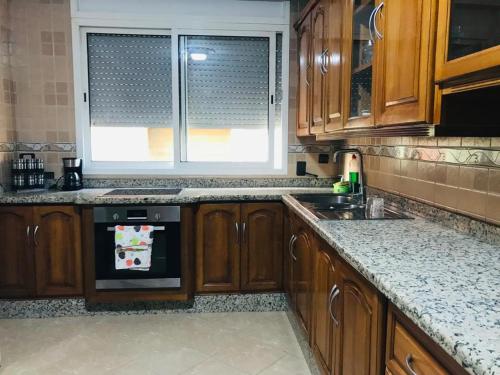 eine Küche mit Holzschränken, einem Waschbecken und einem Fenster in der Unterkunft Apartamento hay amal 12 in Salé