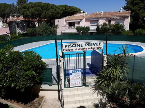 une clôture avec un panneau en face d'une piscine dans l'établissement au cœur des pins, au Cap d'Agde