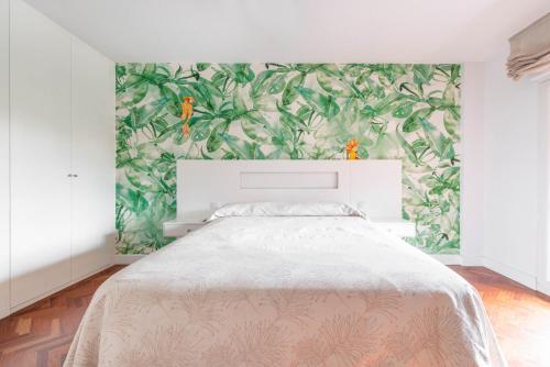a bedroom with a large bed with a green wallpaper at Bonita habitación con balcón in Villaviciosa de Odón