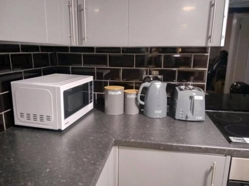 eine Küchentheke mit Mikrowelle und Geräten darauf in der Unterkunft Big spacious 4 Bed House Romford London in Harold Wood
