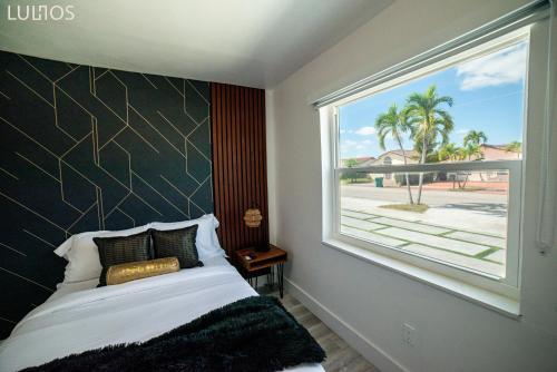 een slaapkamer met een bed en een groot raam bij Miami Chic 6BR Jacuzzi Games, 16 Min to Airport L52 in Tamiami
