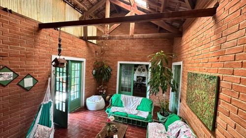 a living room with a green couch and a brick wall at Refúgio Pasárgada Guest House in Mairiporã