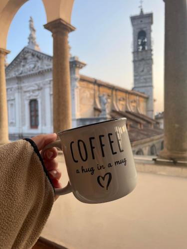 a person holding a coffee cup in front of a building at Holly's House apartment in Alzano Lombardo