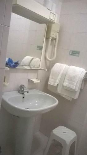 a bathroom with a sink and a mirror and towels at Hotel Du Parc in Atri