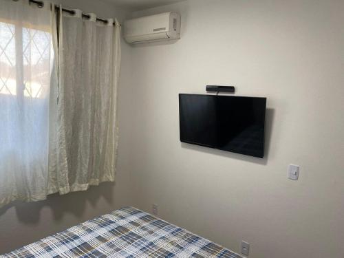 een slaapkamer met een flatscreen-tv aan de muur bij RCM Vilas - STUDIO n 05 in Joinville