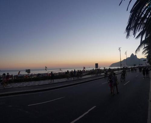 un grupo de personas caminando por una calle junto a la playa en Ipanema Alto Padrão, 03 quartos com suíte, 03 banheiros, portaria 24h, en Río de Janeiro