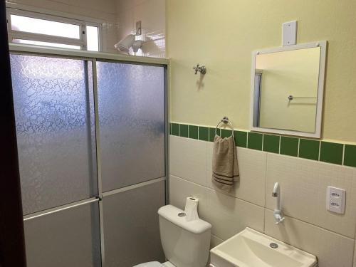 uma casa de banho com um chuveiro, um WC e um espelho. em RCM Vilas - STUDIO n 14 em Joinville