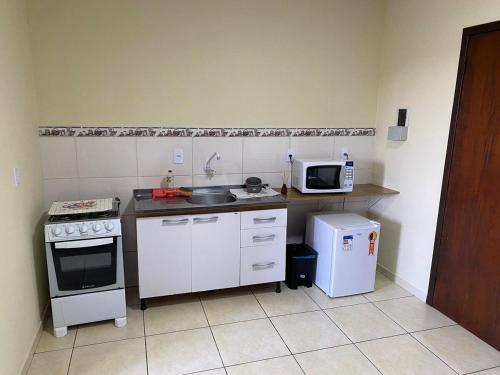 uma pequena cozinha com fogão e micro-ondas em RCM Vilas - STUDIO n 14 em Joinville