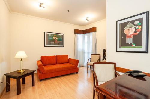 a living room with an orange couch and a table at Travel Inn Flats Jundiaí in Jundiaí