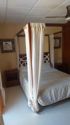 1 dormitorio con cama con dosel y cortinas blancas en Hotel Rural-Restaurante Los Olivos, en Almería