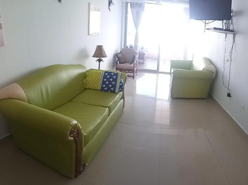 - un salon avec un canapé vert et des chaises dans l'établissement Hermoso departamento frente al mar, à Tonsupa