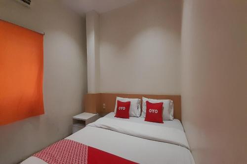 a small room with a bed with two red pillows at OYO 93101 Al-ainah Family Homestay in Medan
