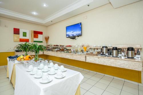 a table with cups and plates on it in a restaurant at Travel Inn Flats Jundiaí in Jundiaí