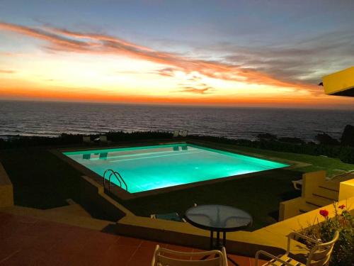 a swimming pool with a view of the ocean at sunset at Herdade AMÁLIA RODRIGUES in Zambujeira do Mar