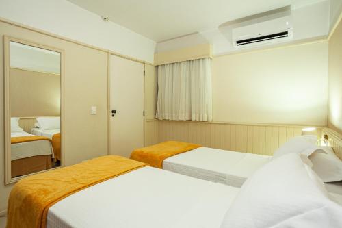 a hotel room with two beds and a mirror at Travel Inn Saint Charles in Jundiaí