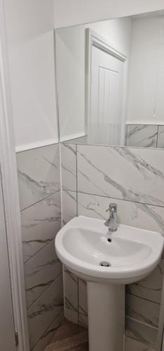 Baño blanco con lavabo y espejo en Cosy Fresh New Refurbished House en Doncaster