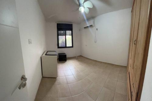 an empty room with a refrigerator and a window at דירת הנופש שלכם in Qiryat Shemona