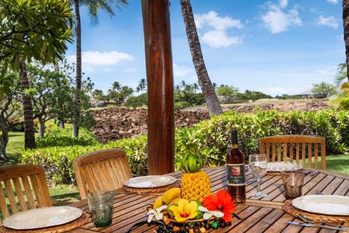 a wooden table with a bottle of wine and fruit on it at Mauna Lani Fairways 1101 in Waikoloa
