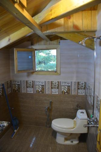 a bathroom with a toilet and a window at Sardar House, Dunga Gali in Dunga Gali