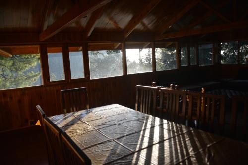 a dining room with a table and some windows at Sardar House, Dunga Gali in Dunga Gali