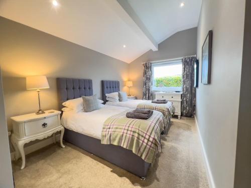 a bedroom with two beds and a window at Lake View luxury home with Lake Ullswater view & 2 ground floor bedrooms ideal for 2 families in Watermillock