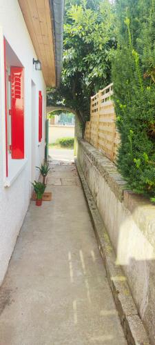 a sidewalk next to a building with a red window at Home Sweet Home in Bouglainval