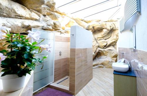 a bathroom with a stone wall with a toilet and a plant at Vila24 Levice in Levice
