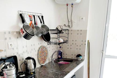 eine Küchentheke mit Töpfen und Pfannen an der Wand in der Unterkunft Appartement à M'diq in Mʼdik