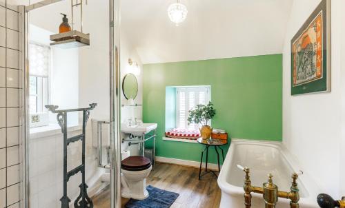 een badkamer met groene muren, een bad en een wastafel bij Delightful Cotswold Cottage for two, Log Burner, Garden & Dog Friendly in Northleach