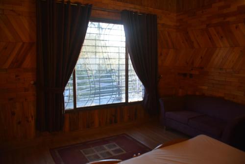 a bedroom with a window with a couch and a chair at Sardar House, Dunga Gali in Dunga Gali