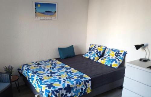 a small bedroom with a bed with blue and yellow sheets at Charmant studio climatisé 24 m2 terrasse à 100m de la plage in Saint-Mandrier-sur-Mer