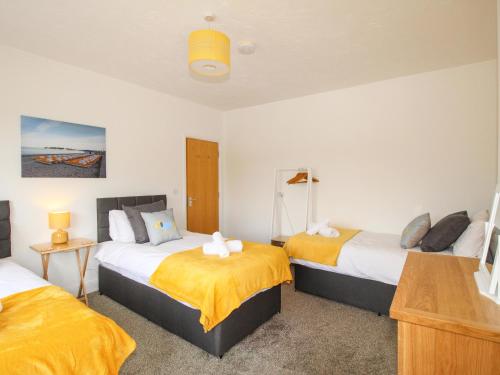 una camera con due letti con lenzuola gialle di The White Cottage a Weymouth