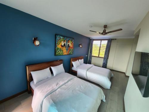 a bedroom with two beds and a blue wall at ALERI'S GARDEN in Big Ada